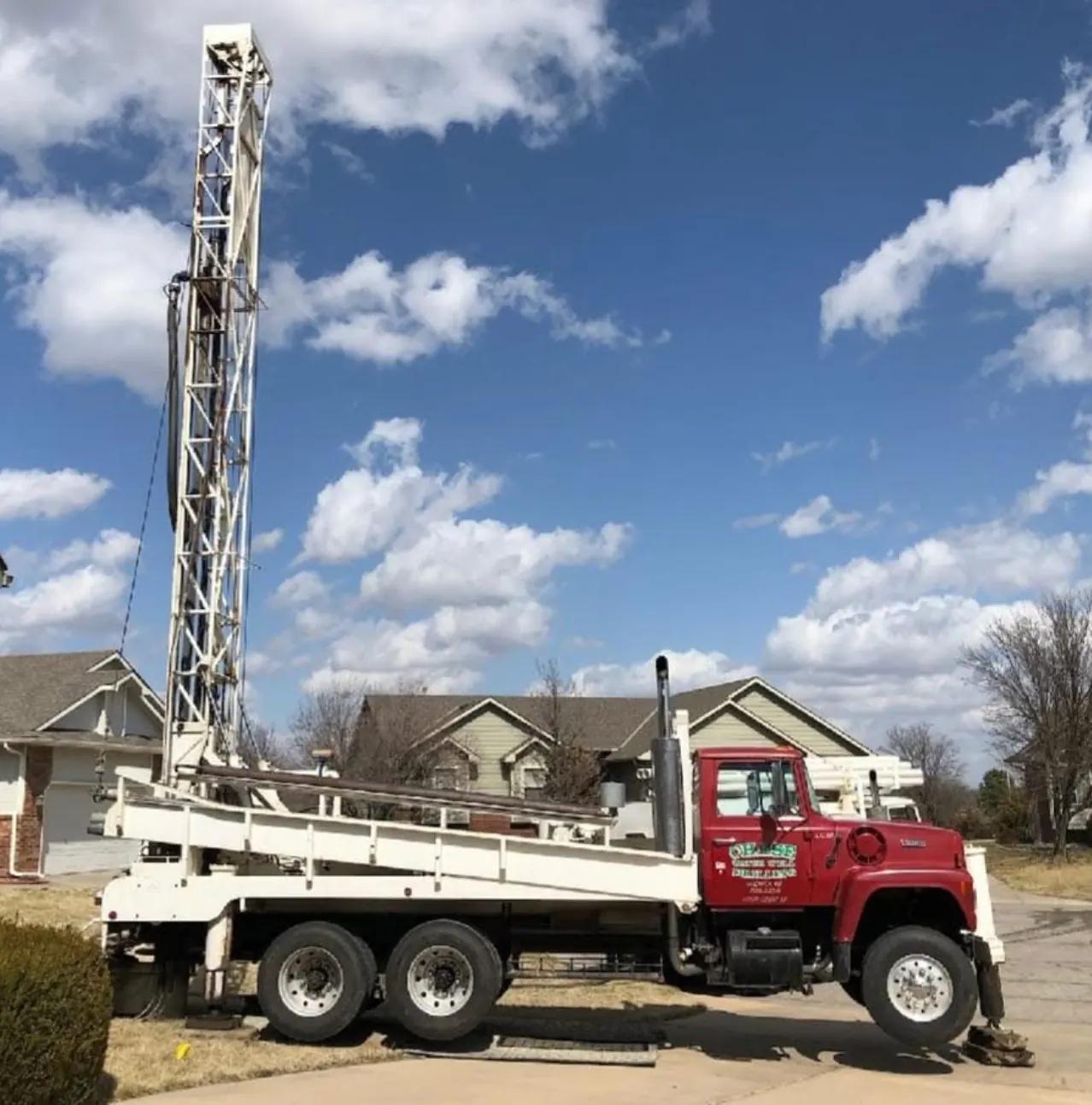 Chase Drilling LLC residential water well drilling rig positioned at a Wichita, KS home, with the drill mast raised and crew preparing to drill a new private water well