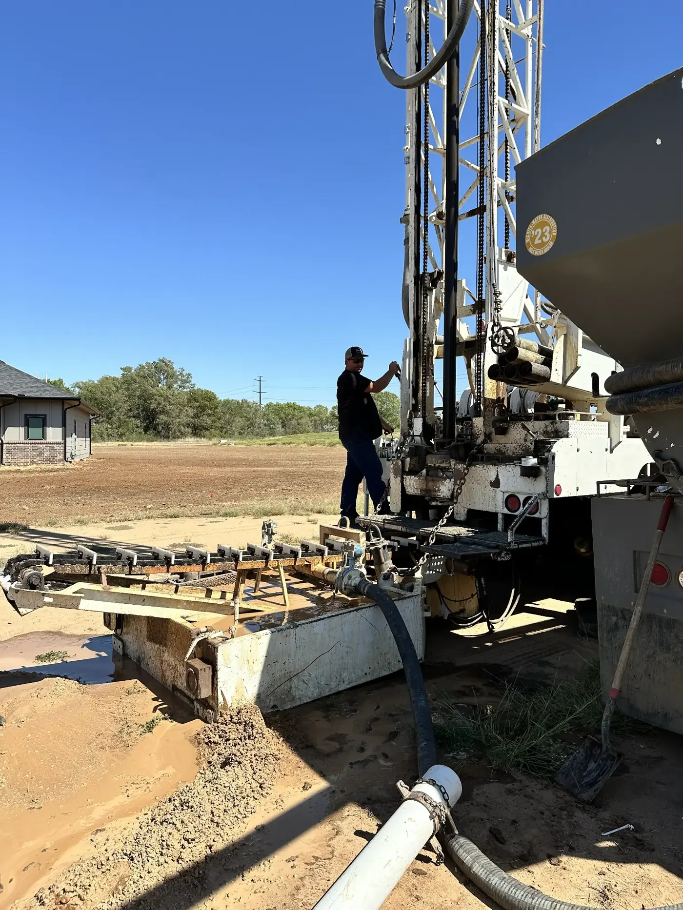 Completed water well pump installation at a Kansas property showing the wellhead, pressure tank, and electrical connections installed by Chase Drilling LLC
